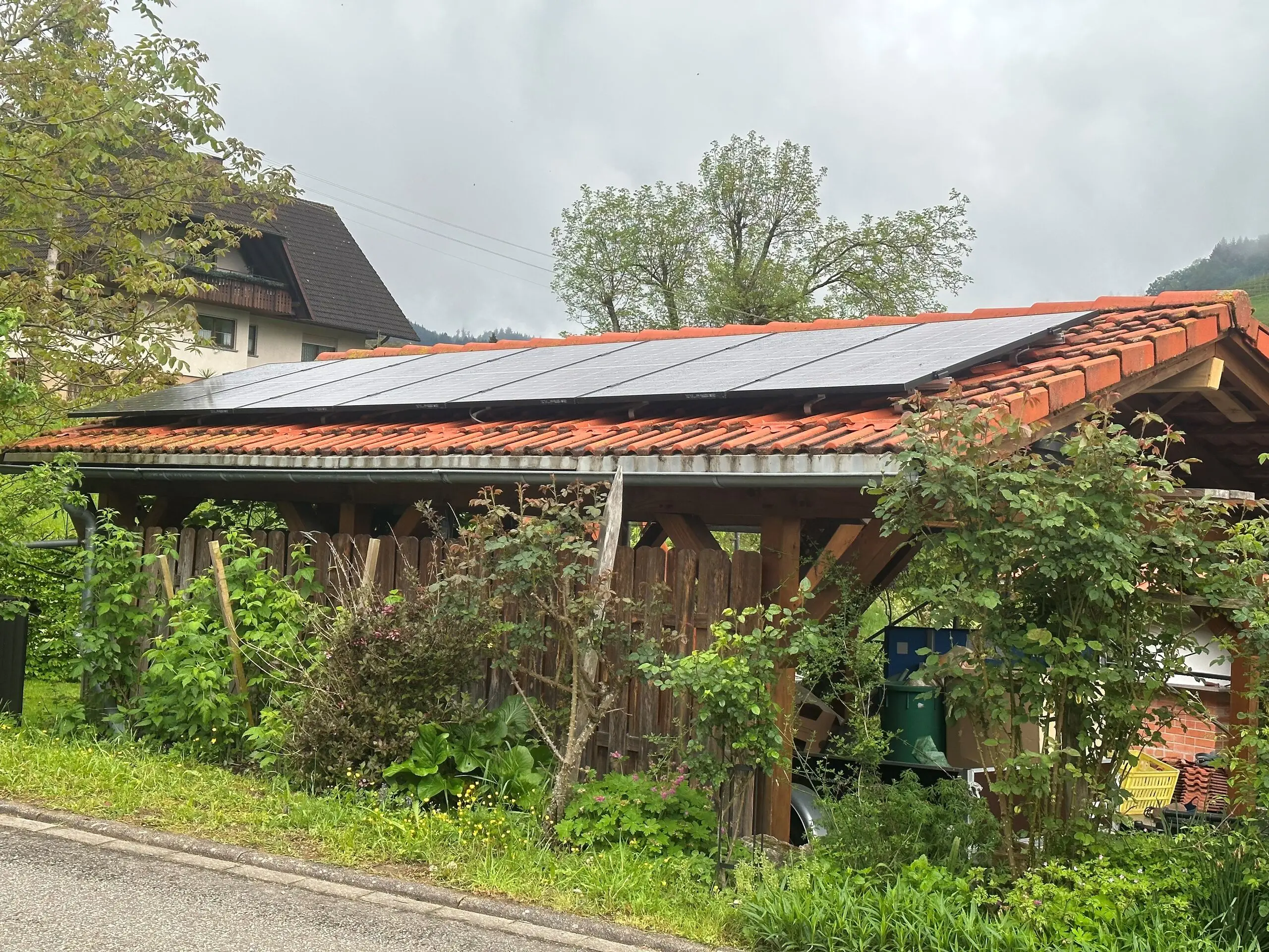 Photovoltaikmodule auf dem Ziegeldach eines hölzernen Carports